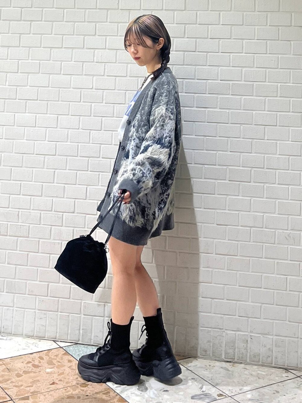 ブラック系のブーツ、ホワイト系のカーディガン/ボレロ、ホワイト系のニット/セーターを着用したレディースの冬コーディネートの2枚目の写真