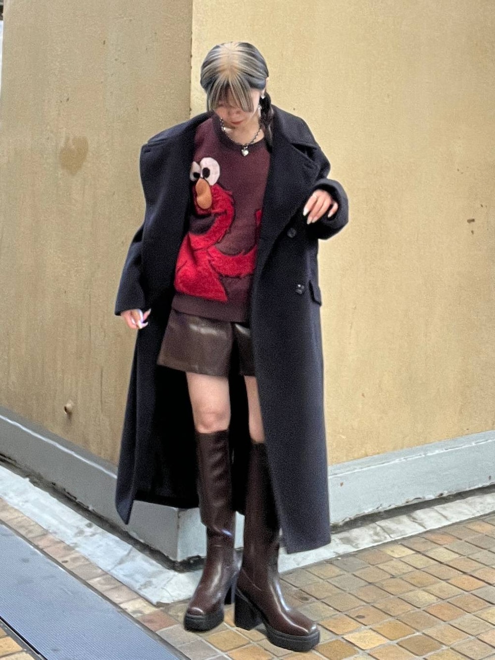 ブラック系のチェスターコート、ブラウン系のブーツ、ブラウン系のその他パンツを着用したレディースの冬コーディネートの4枚目の写真