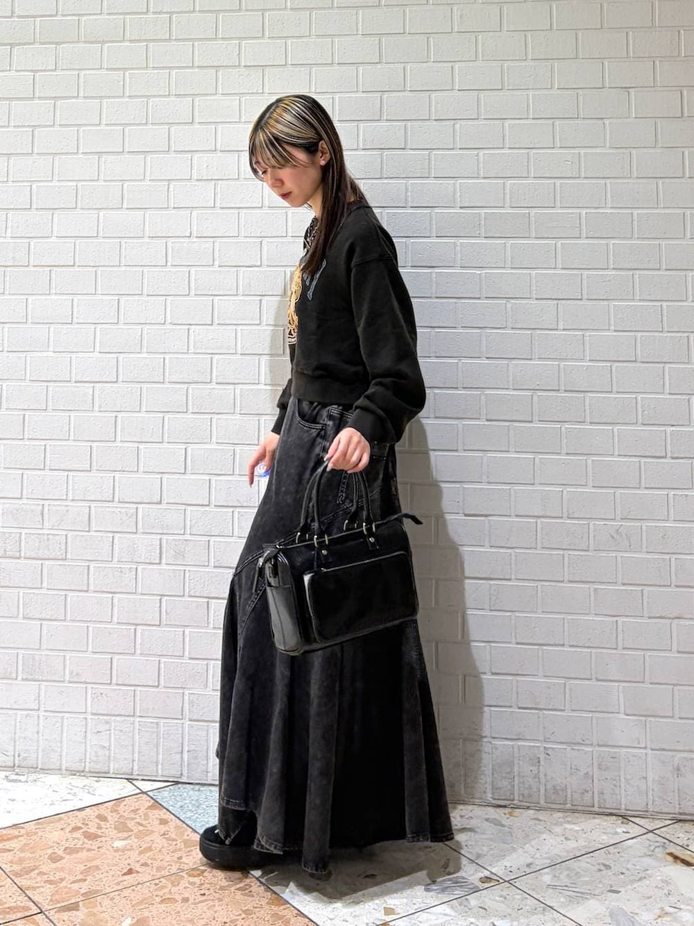 グレー系のスウェット、ブラック系のショルダーバッグ、ブラック系のデニムスカートを着用したレディースの春コーディネートの2枚目の写真