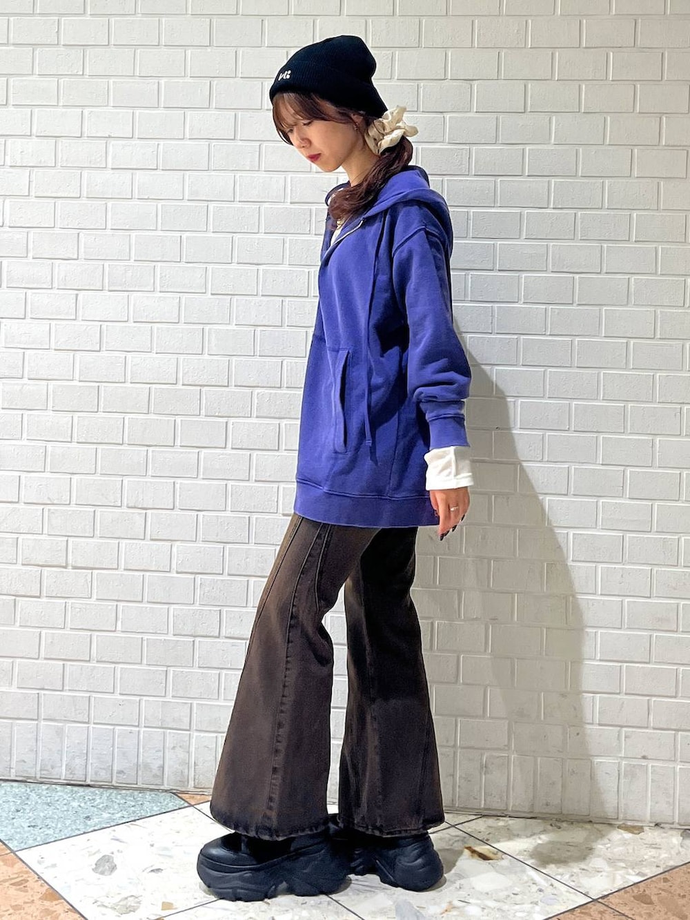 ブラック系のブーツ、ブラウン系のデニムパンツ、ブルー系のパーカーを着用したレディースの秋コーディネートの2枚目の写真