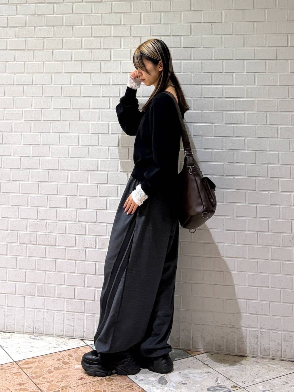 ブラック系のブーツ、ブラック系のニット/セーター、ブラウン系のショルダーバッグを着用したレディースの冬コーディネートの3枚目の写真