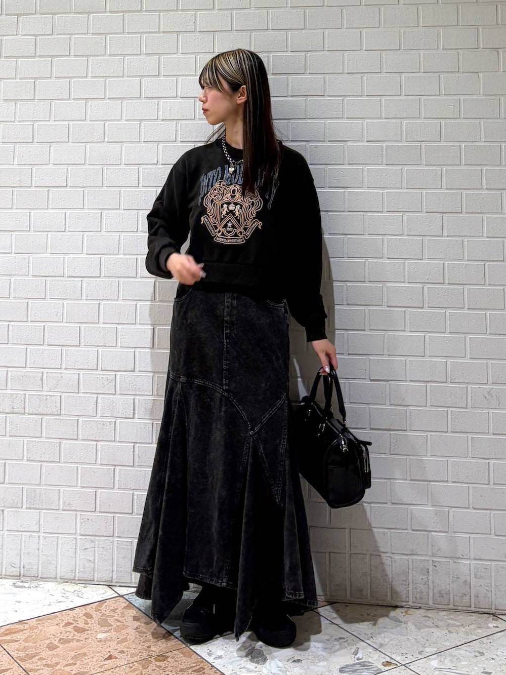 グレー系のスウェット、ブラック系のショルダーバッグ、ブラック系のデニムスカートを着用したレディースの春コーディネートの7枚目の写真