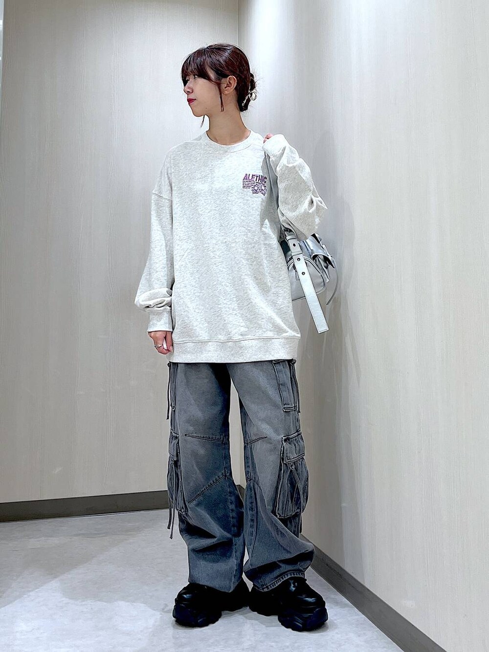 ブラック系のデニムパンツ、シルバー系のショルダーバッグ、ベージュ系のスウェットを着用したレディースの秋コーディネートの2枚目の写真