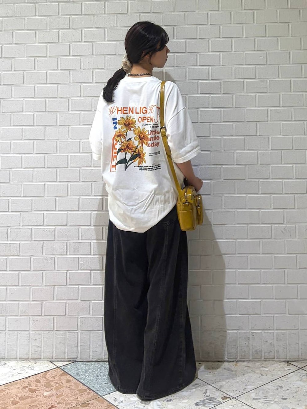 ブラック系のデニムパンツ、イエロー系のショルダーバッグ、ホワイト系のTシャツ/カットソーを着用したレディースの夏コーディネートの6枚目の写真