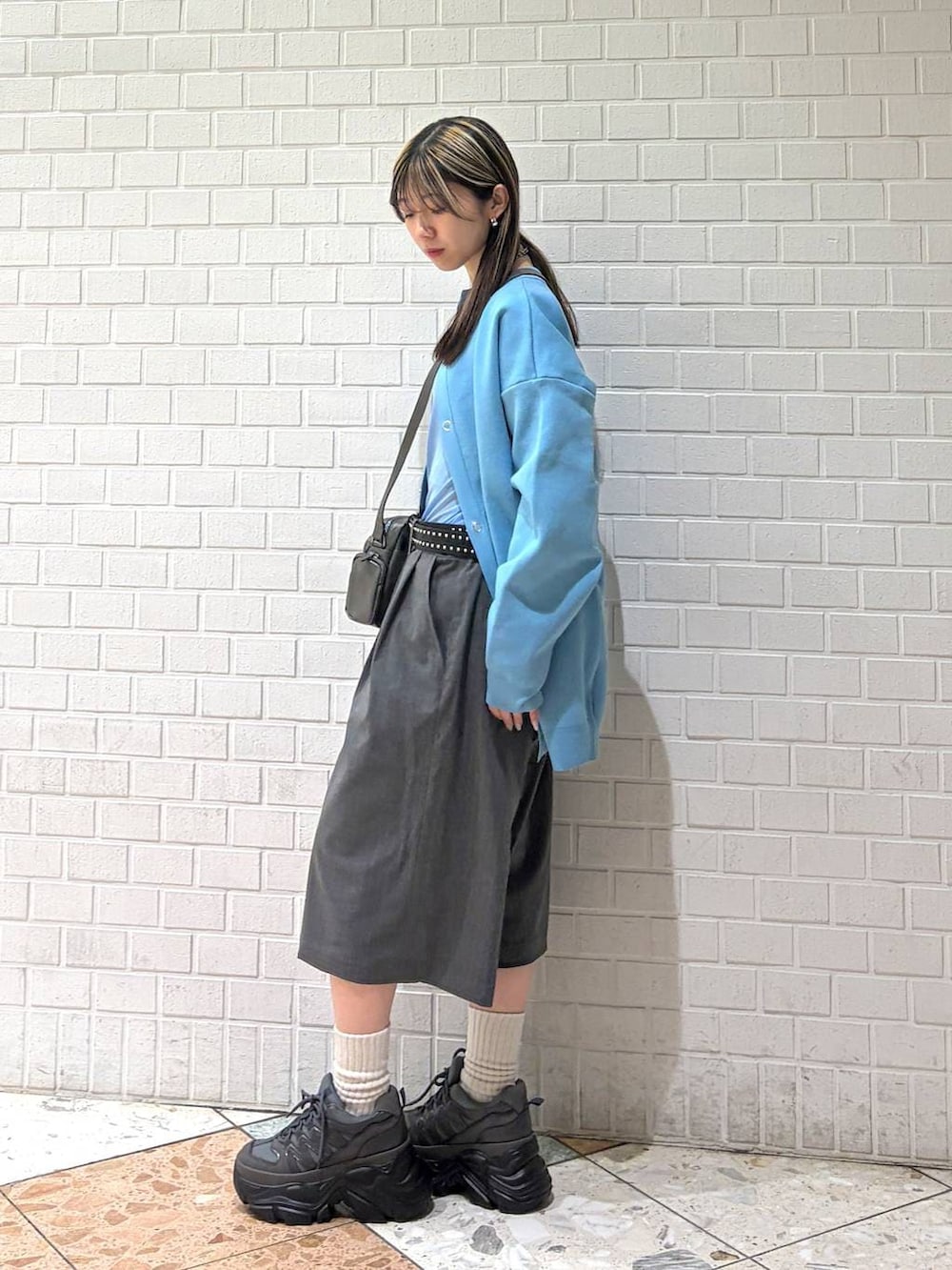 グレー系のスニーカー、グレー系のショルダーバッグ、グレー系のスラックスを着用したレディースの春コーディネートの2枚目の写真