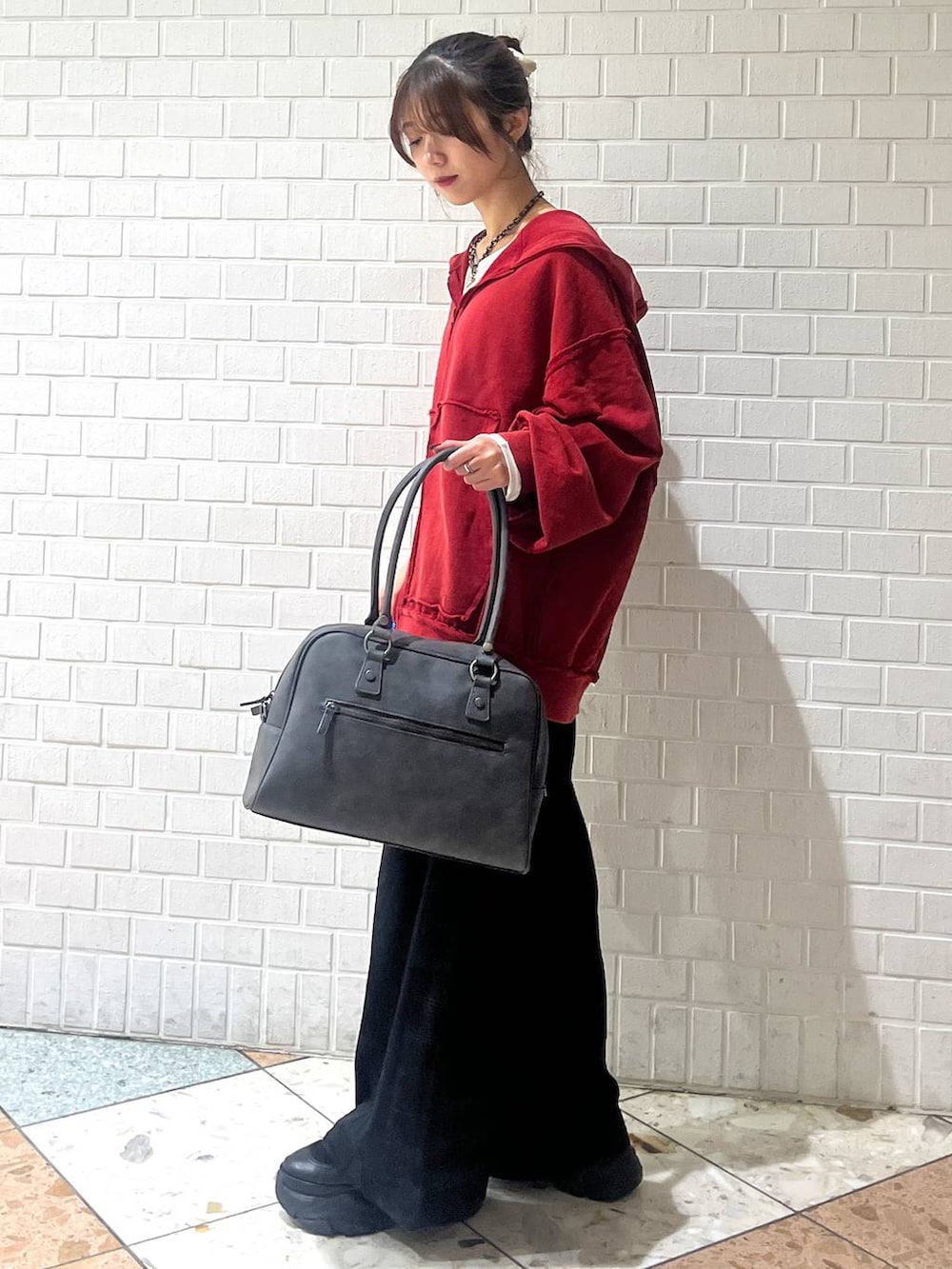 ブラック系のブーツ、グレー系のボストンバッグ、ブラック系のスラックスを着用したレディースの秋コーディネートの2枚目の写真