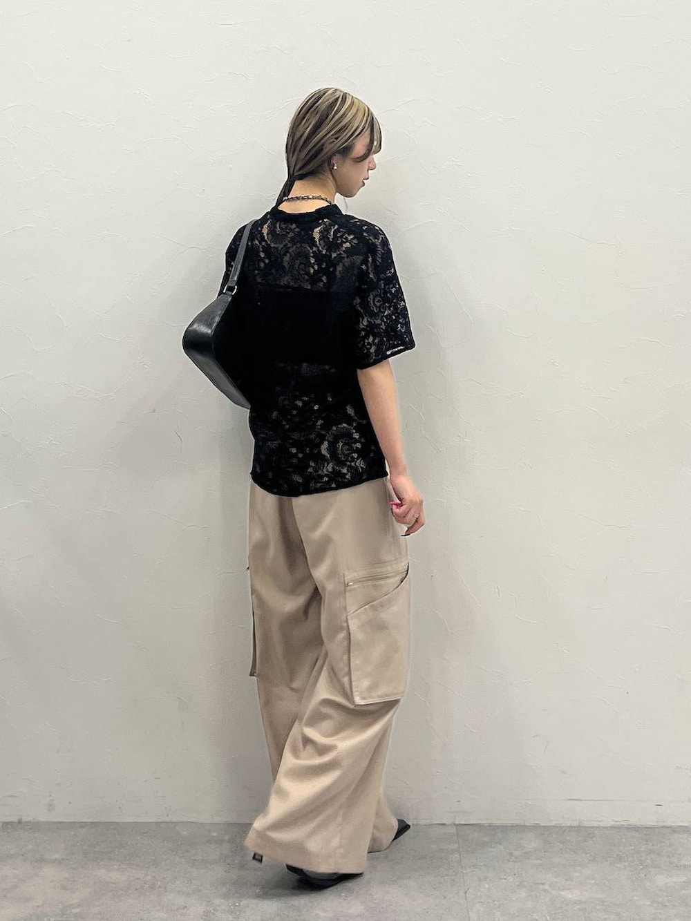 ブラック系のシャツ/ブラウス、ベージュ系のスラックス、ブラック系のハンドバッグを着用したレディースの春コーディネートの2枚目の写真