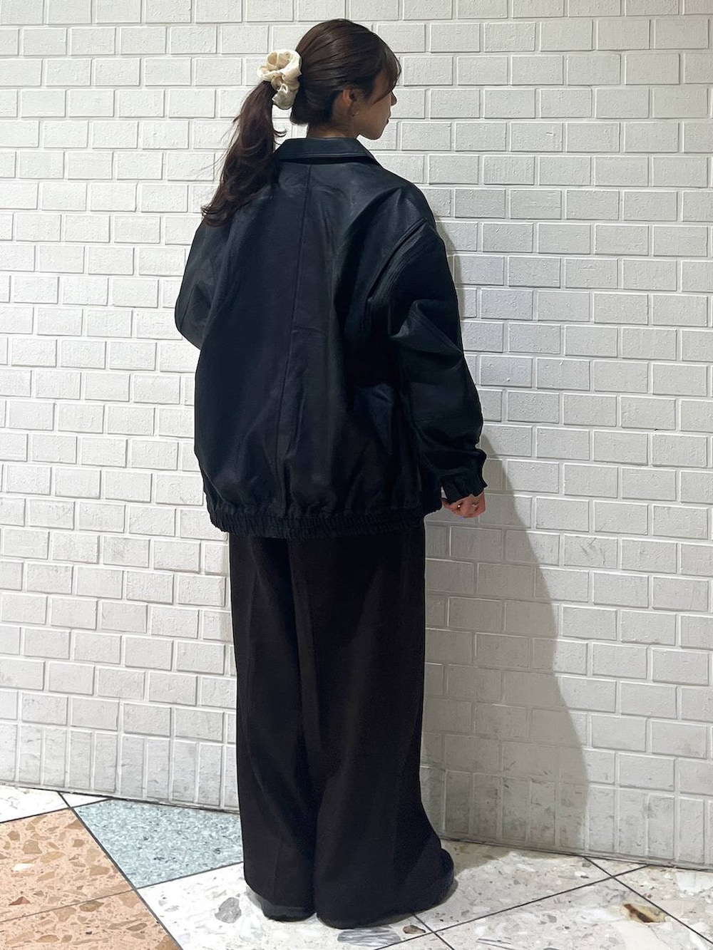 ブラック系のスニーカー、ブラック系のブルゾン、ホワイト系のカーディガン/ボレロを着用したレディースの秋コーディネートの3枚目の写真