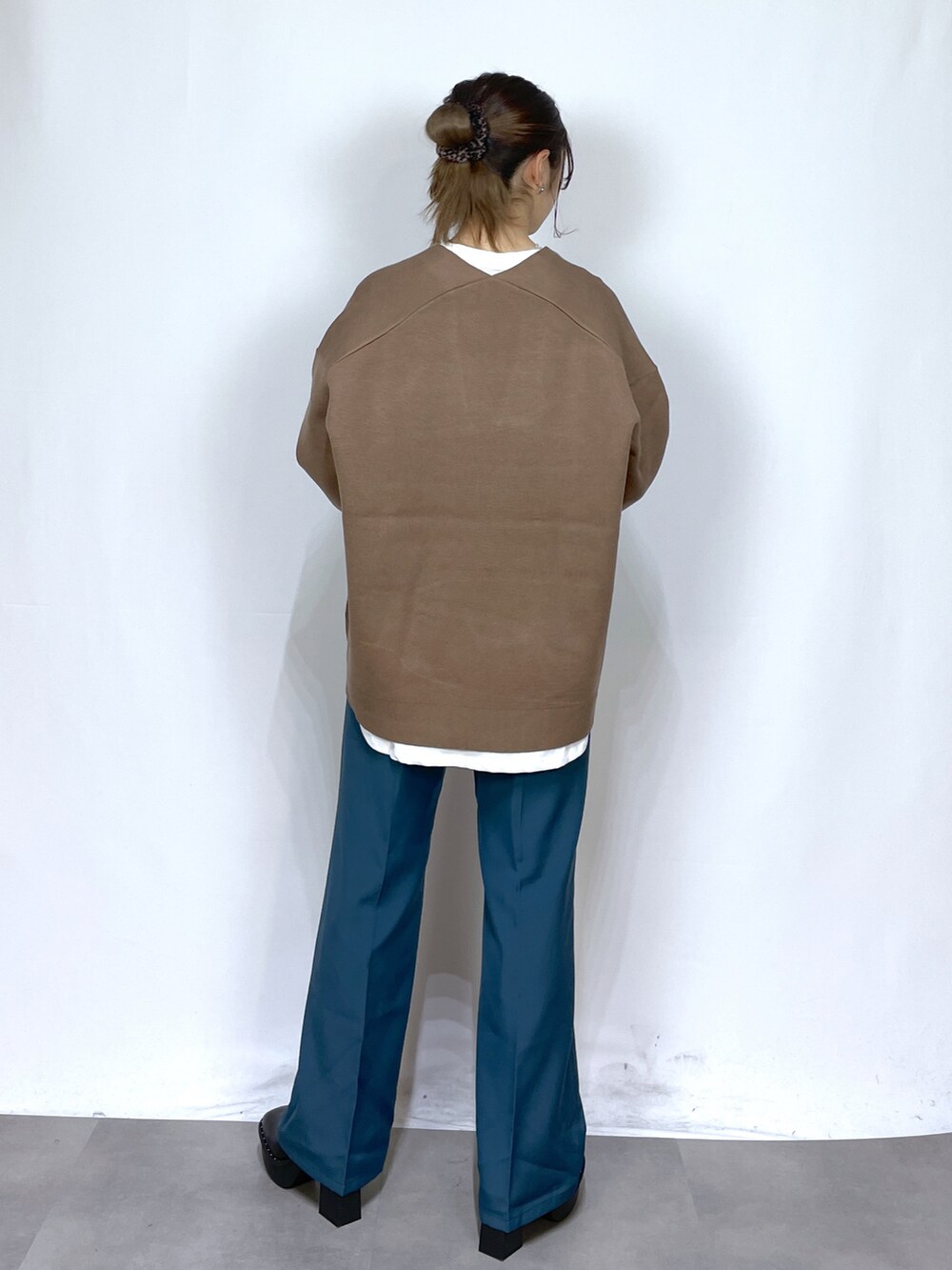 ホワイト系のTシャツ/カットソー、ブラウン系のニット/セーター、ブルー系のスラックスを着用したレディースの冬コーディネートの4枚目の写真