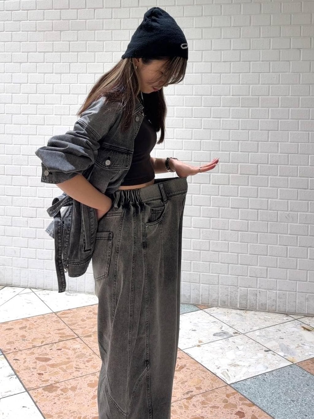 ホワイト系のスニーカー、ブラック系のブルゾン、ブラック系のデニムパンツを着用したレディースの春コーディネートの4枚目の写真