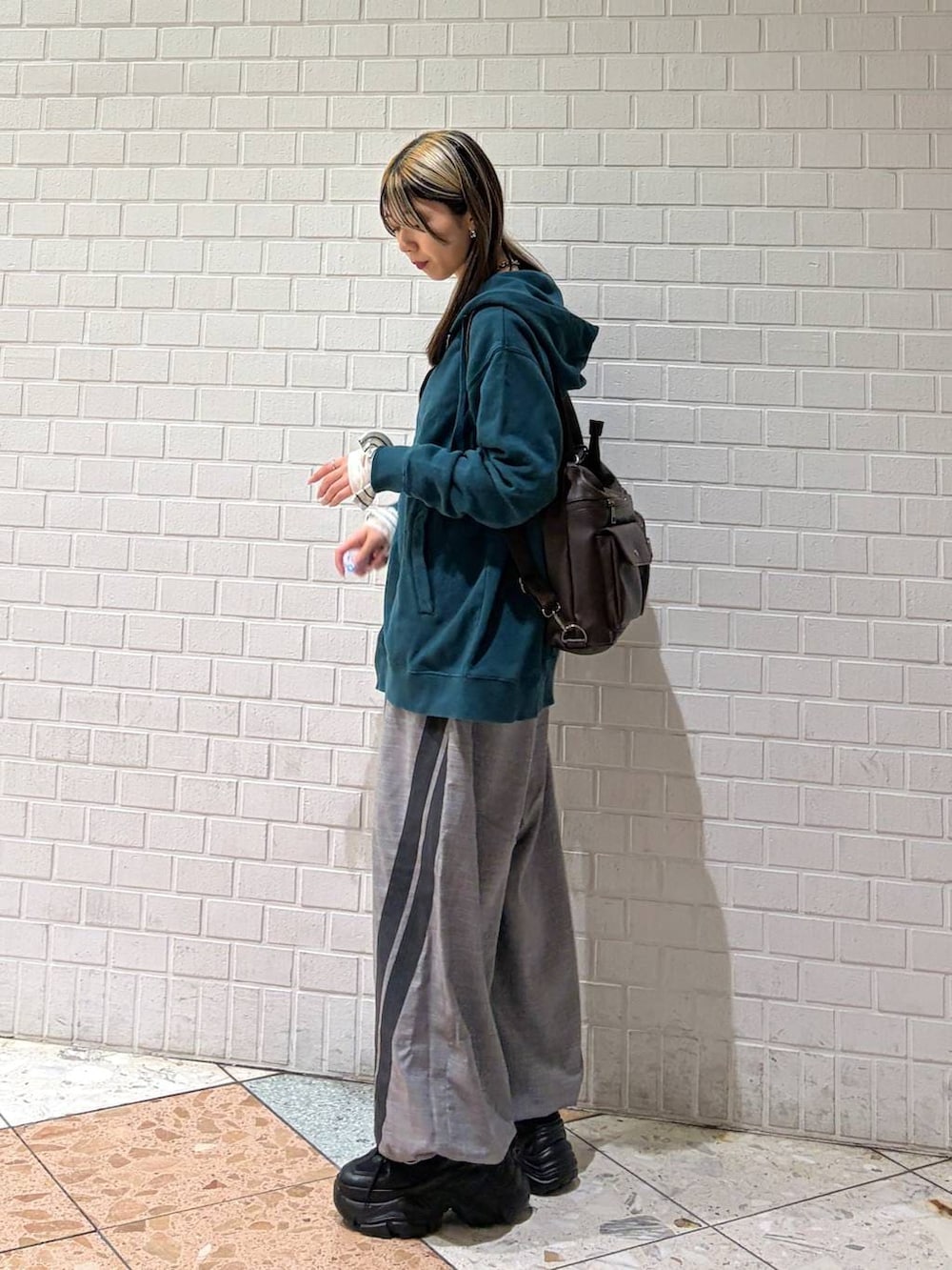 ブラック系のブーツ、グリーン系のパーカー、ブラウン系のショルダーバッグを着用したレディースの冬コーディネートの3枚目の写真