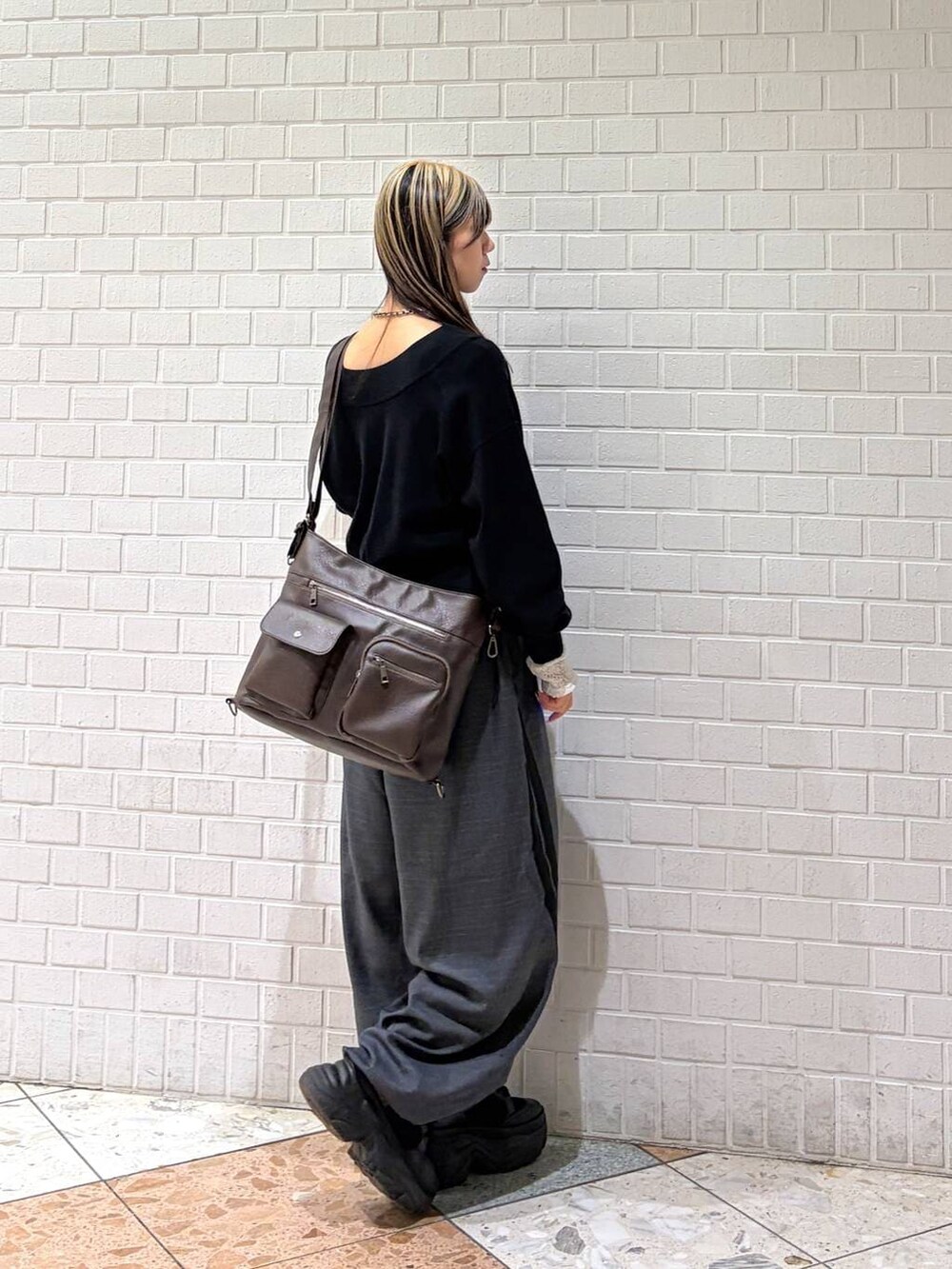 ブラック系のブーツ、ブラック系のニット/セーター、ブラウン系のショルダーバッグを着用したレディースの冬コーディネートの2枚目の写真