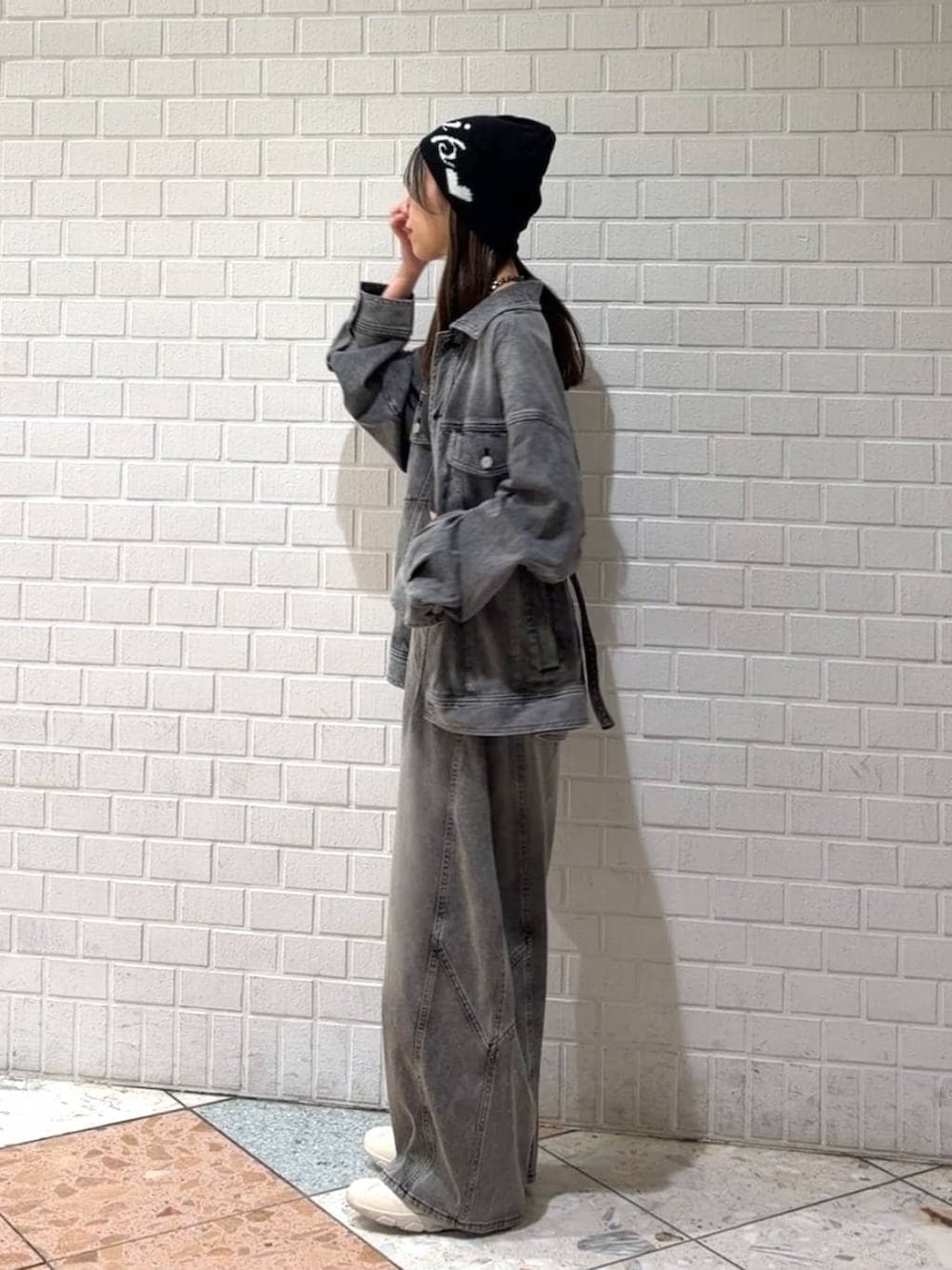 ホワイト系のスニーカー、ブラック系のブルゾン、ブラック系のデニムパンツを着用したレディースの春コーディネートの6枚目の写真