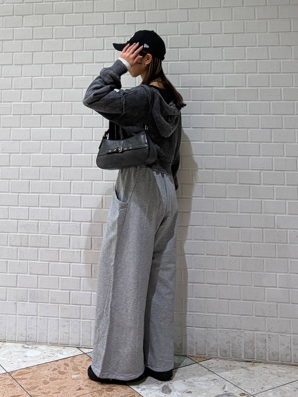 ブラック系のハンドバッグ、グレー系のスウェットパンツ、グレー系のパーカーを着用したレディースの冬コーディネートの3枚目の写真