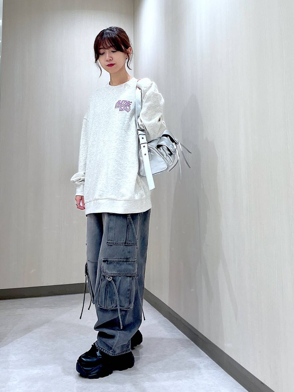 ブラック系のデニムパンツ、シルバー系のショルダーバッグ、ベージュ系のスウェットを着用したレディースの秋コーディネートの3枚目の写真