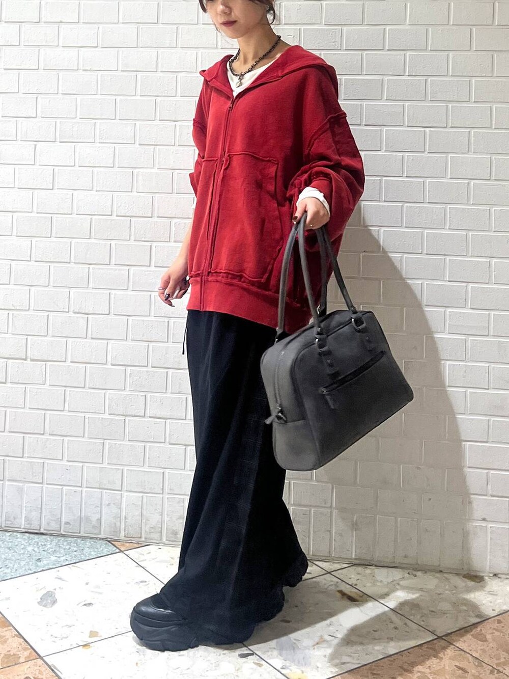 ブラック系のブーツ、グレー系のボストンバッグ、ブラック系のスラックスを着用したレディースの秋コーディネートの4枚目の写真