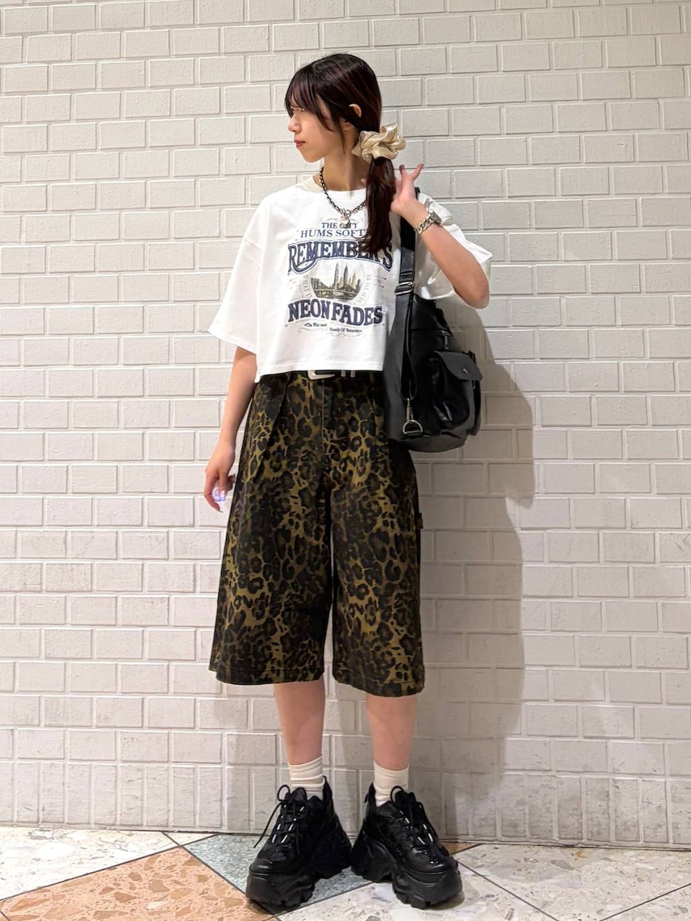 ブラック系のスニーカー、ブラック系のショルダーバッグ、ホワイト系のTシャツ/カットソーを着用したレディースの夏コーディネートの4枚目の写真