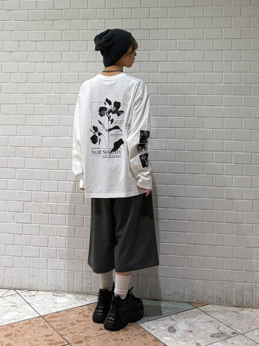 ブラック系のスニーカー、ホワイト系のTシャツ/カットソー、グレー系のスラックスを着用したレディースの春コーディネートの2枚目の写真