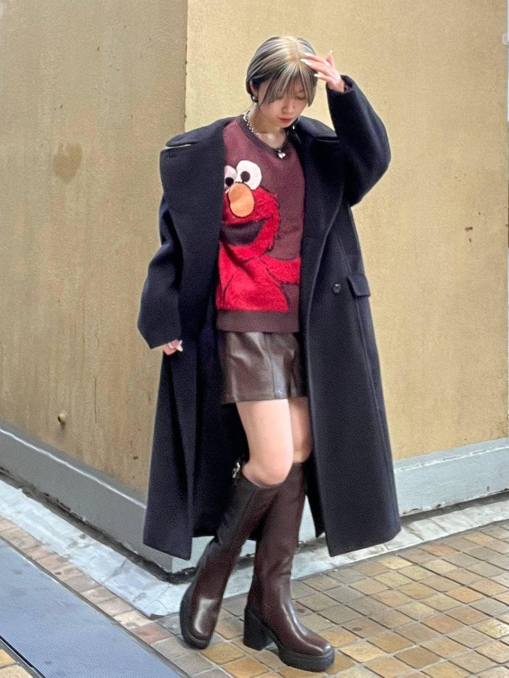 ブラック系のチェスターコート、ブラウン系のブーツ、ブラウン系のその他パンツを着用したレディースの冬コーディネートの5枚目の写真