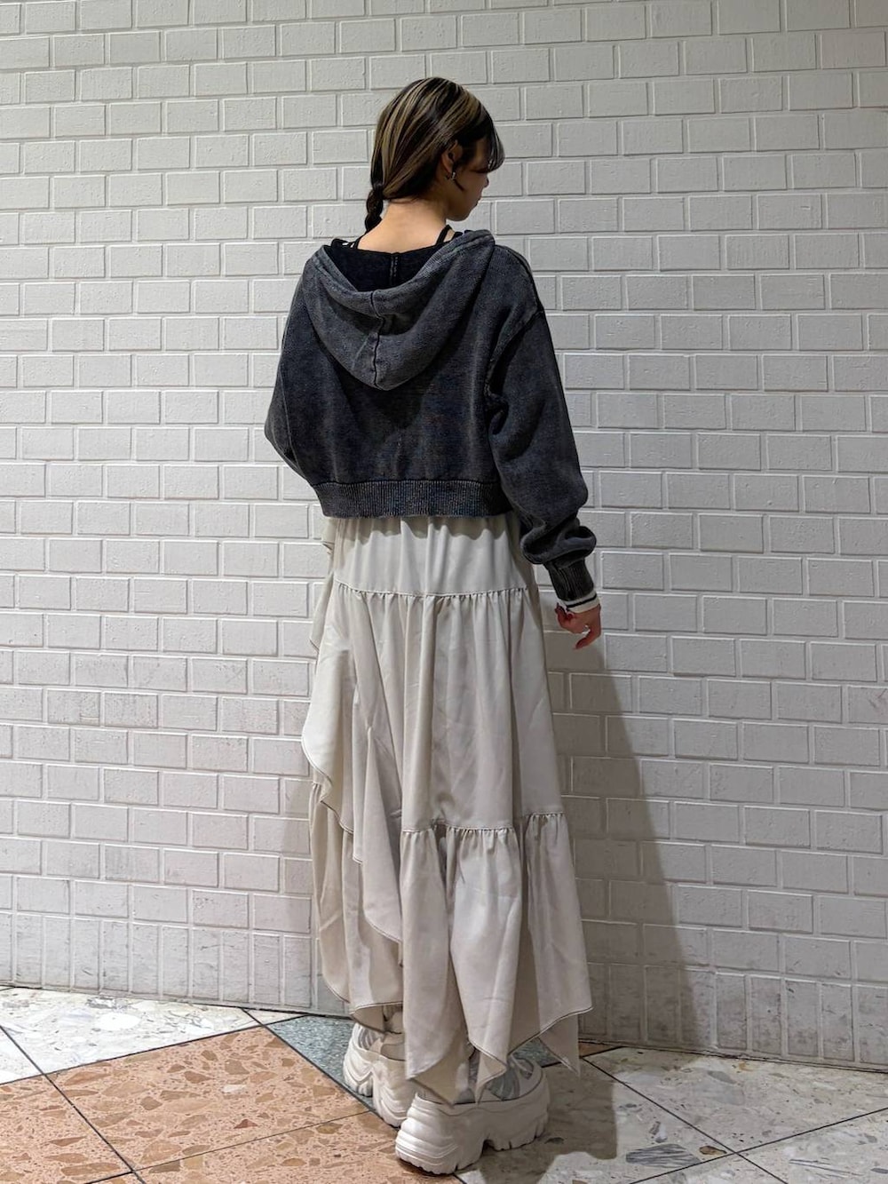 ホワイト系のスニーカー、ベージュ系のスカート、ホワイト系のボストンバッグを着用したレディースの冬コーディネートの3枚目の写真