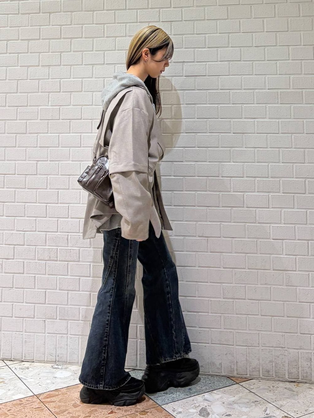 ブラック系のブーツ、ブルー系のデニムパンツ、グレー系のパーカーを着用したレディースの春コーディネートの7枚目の写真