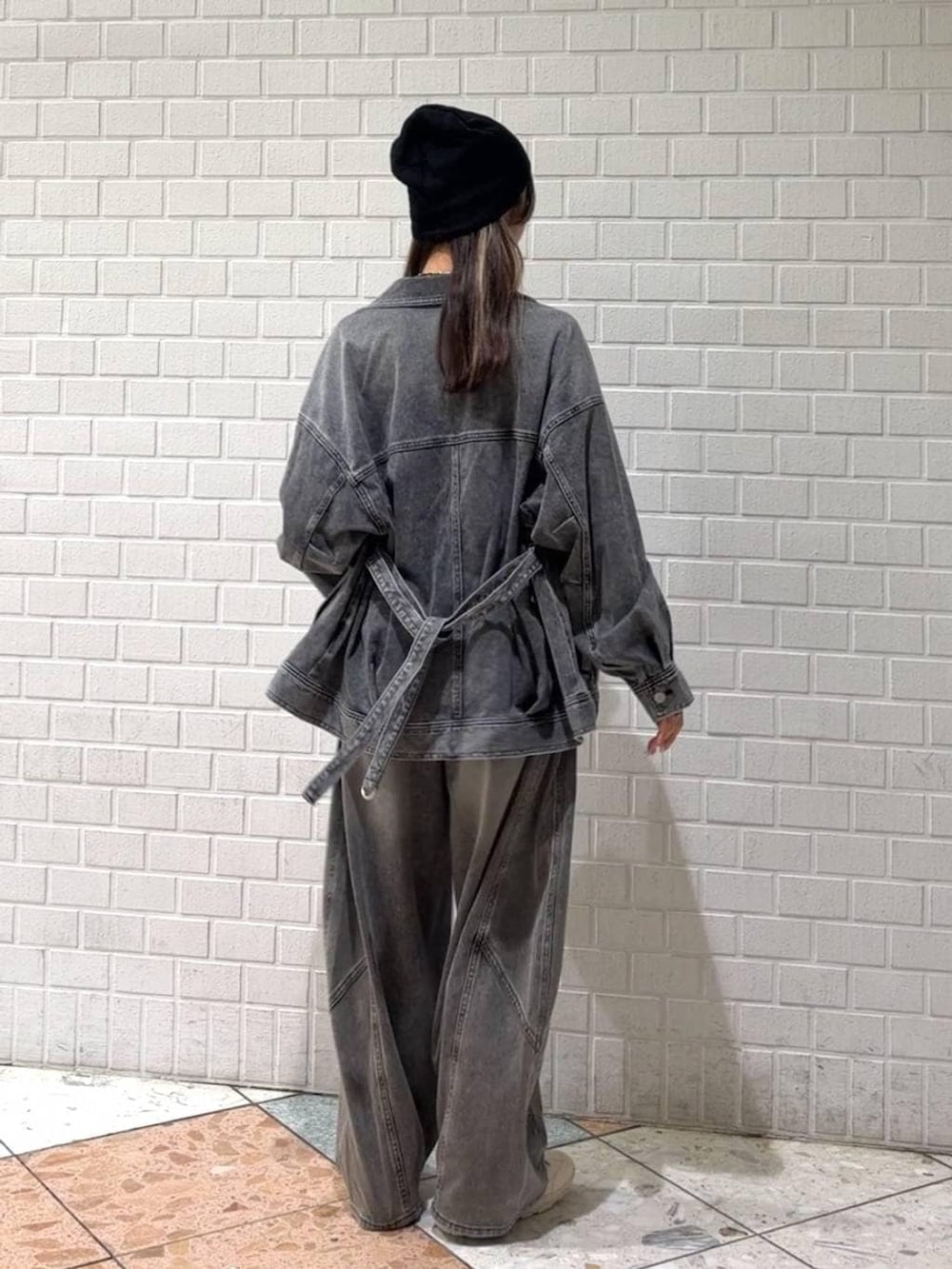 ホワイト系のスニーカー、ブラック系のブルゾン、ブラック系のデニムパンツを着用したレディースの春コーディネートの5枚目の写真