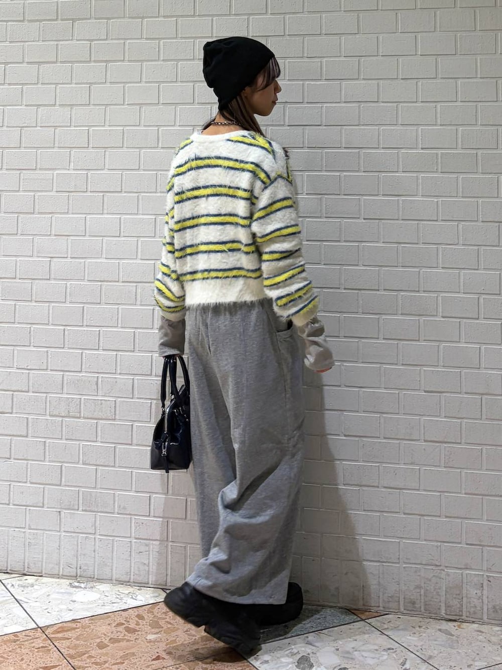 ブラック系のブーツ、ブルー系のハンドバッグ、ホワイト系のニット/セーターを着用したレディースの冬コーディネートの5枚目の写真