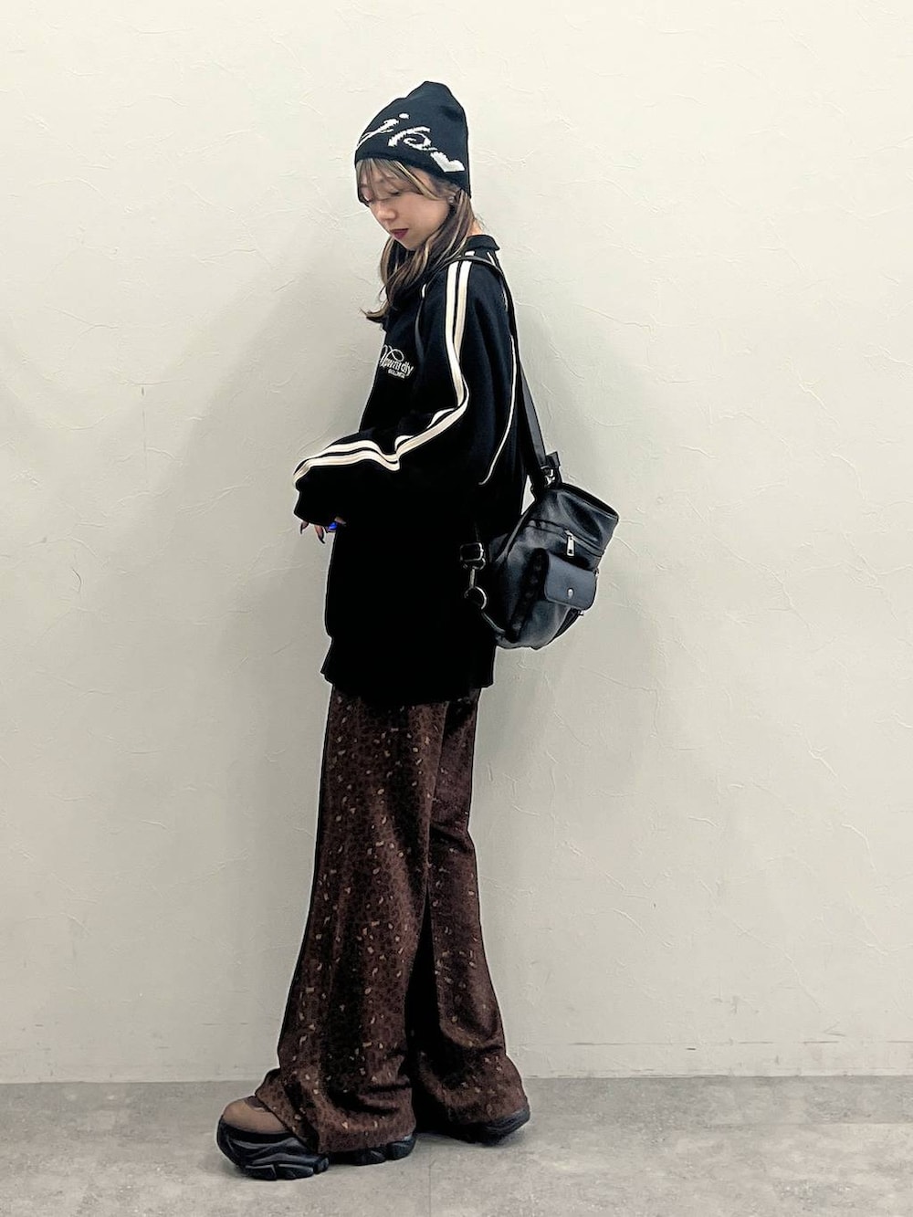 ブラウン系のブーツ、ブラック系のショルダーバッグ、ブラック系のジャージを着用したレディースの冬コーディネートの2枚目の写真