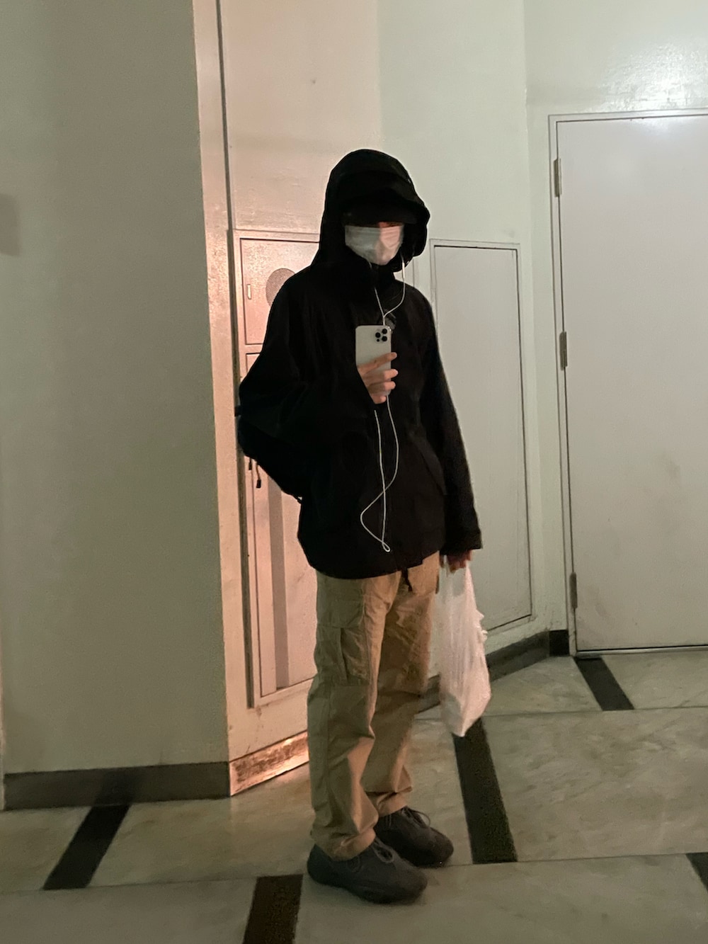 ブラック系のマウンテンパーカー、ベージュ系のカーゴパンツ、グレー系のスニーカーを着用したメンズの春コーディネートの2枚目の写真