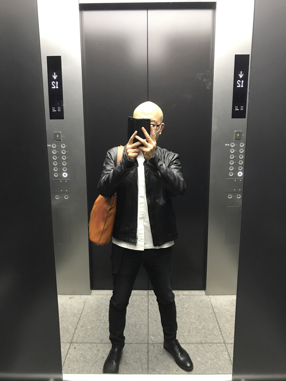 ブルー系のデニムパンツ、ブラック系のライダースジャケット、ホワイト系のビジネスシャツを着用したメンズの春コーディネートの2枚目の写真