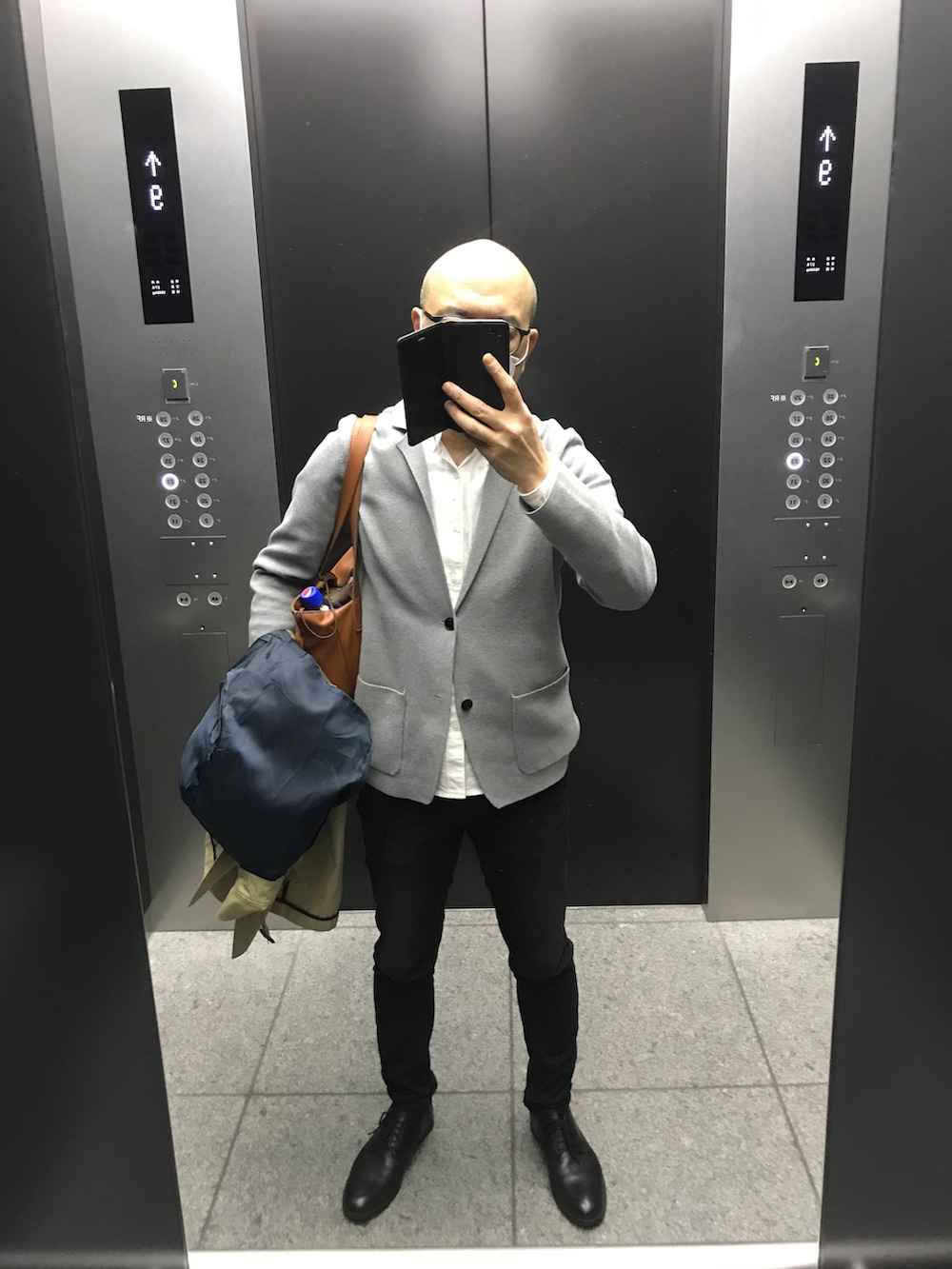 グレー系のテーラードジャケット、ブルー系のデニムパンツ、ブラック系のドレスシューズを着用したメンズの春コーディネートの2枚目の写真