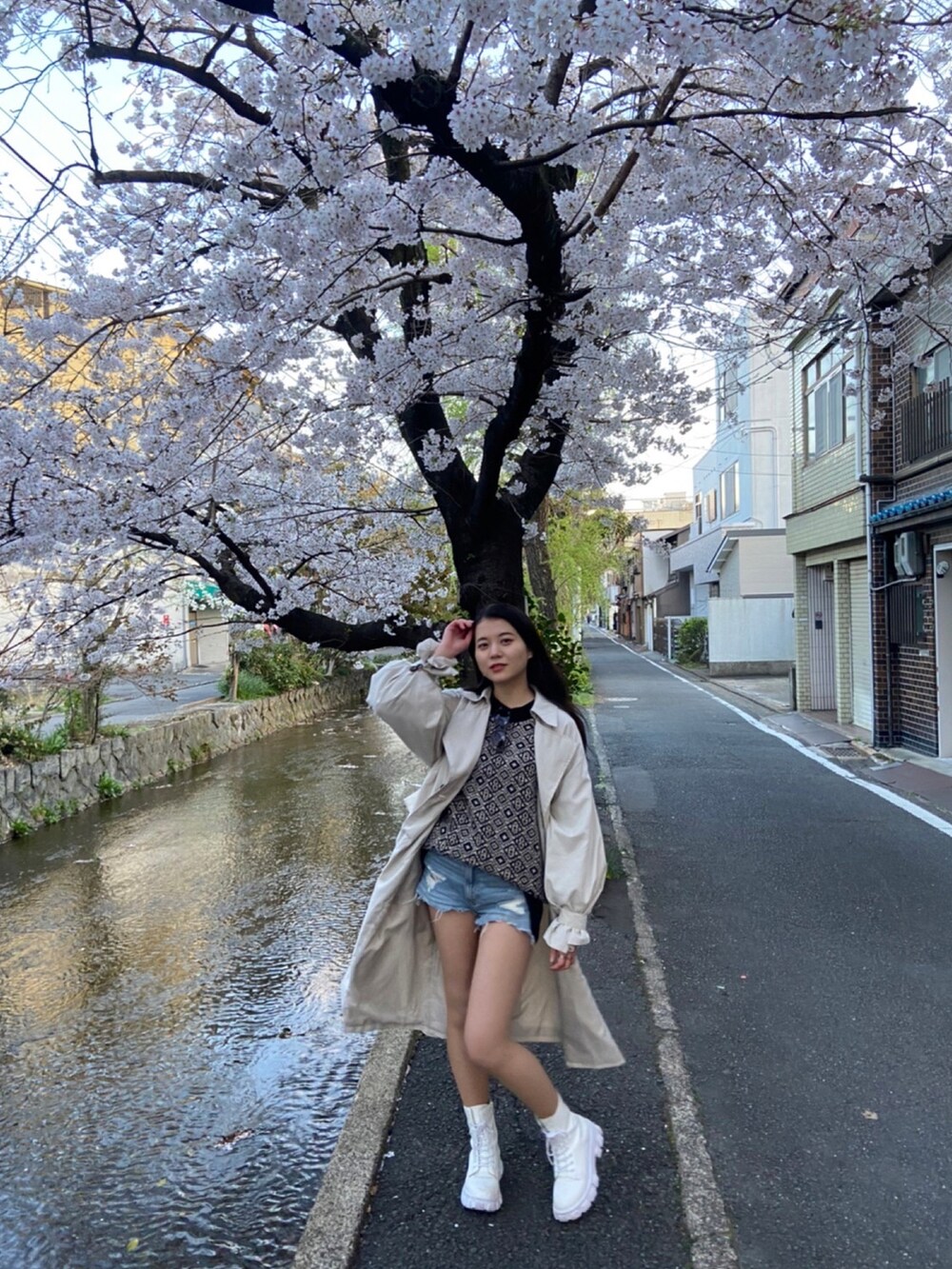 ブラック系のニット/セーター、ベージュ系のトレンチコートを着用したレディースの春コーディネートの3枚目の写真