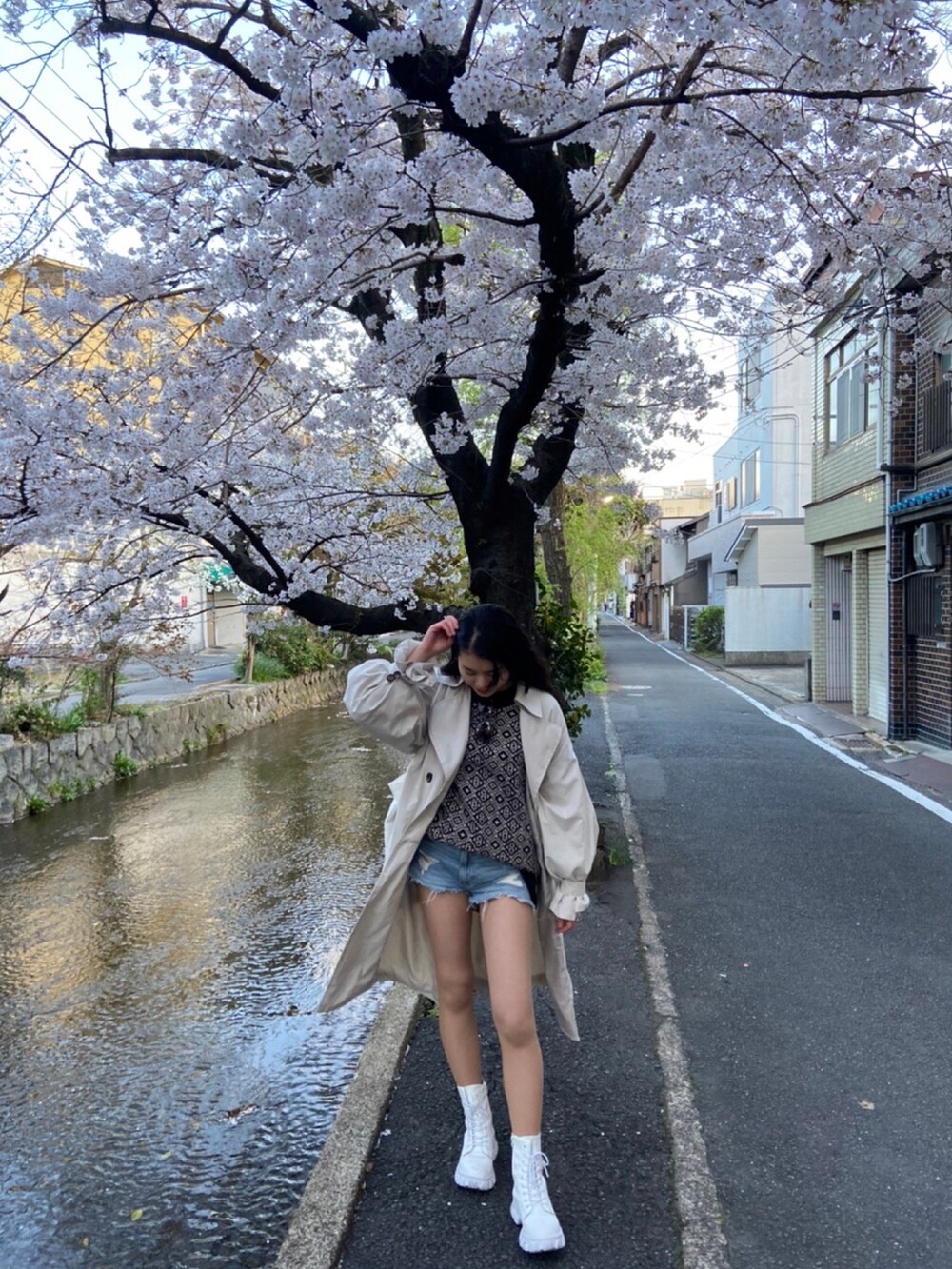 ブラック系のニット/セーター、ベージュ系のトレンチコートを着用したレディースの春コーディネートの2枚目の写真