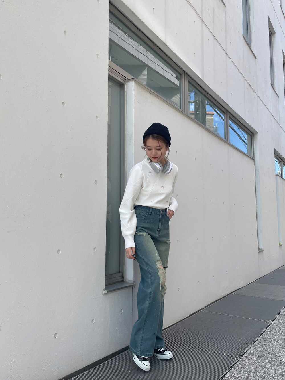 ブラック系のスニーカー、ブルー系のデニムパンツ、ホワイト系のニット/セーターを着用したレディースの秋コーディネートの3枚目の写真