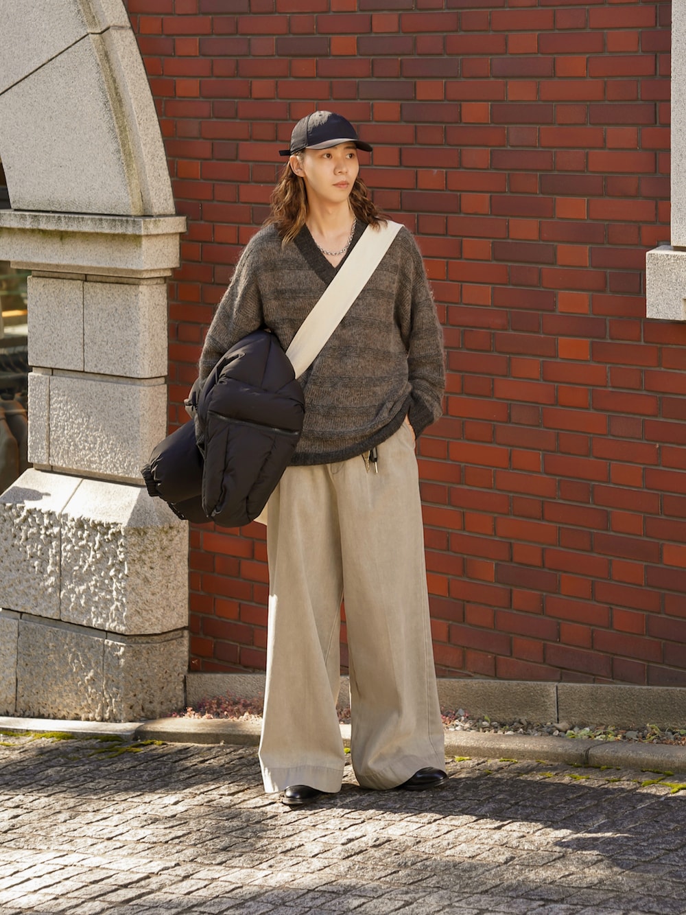 グレー系のデニムパンツ、ブラック系のドレスシューズ、グレー系のニット/セーターを着用したメンズの秋コーディネートの4枚目の写真