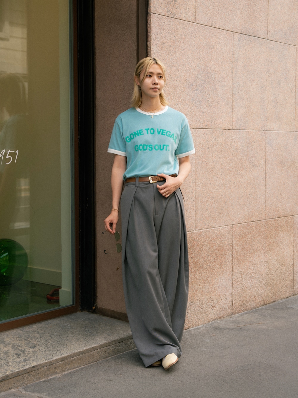 ブルー系のTシャツ/カットソー、グレー系のスラックス、ホワイト系のサンダルを着用したメンズの夏コーディネートの2枚目の写真
