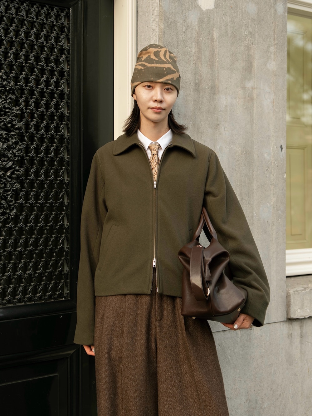 ブラウン系のスラックス、グリーン系のジャケット/アウター、ブラウン系のボストンバッグを着用したメンズの秋コーディネートの3枚目の写真