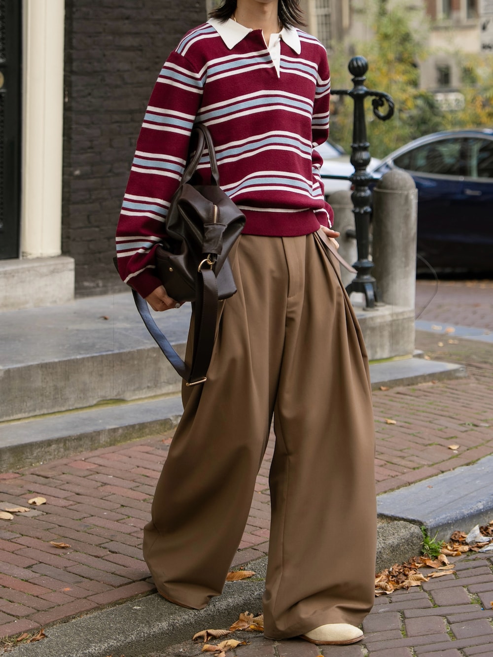 レッド系のポロシャツ、ブラウン系のスラックスを着用したメンズの秋コーディネートの3枚目の写真