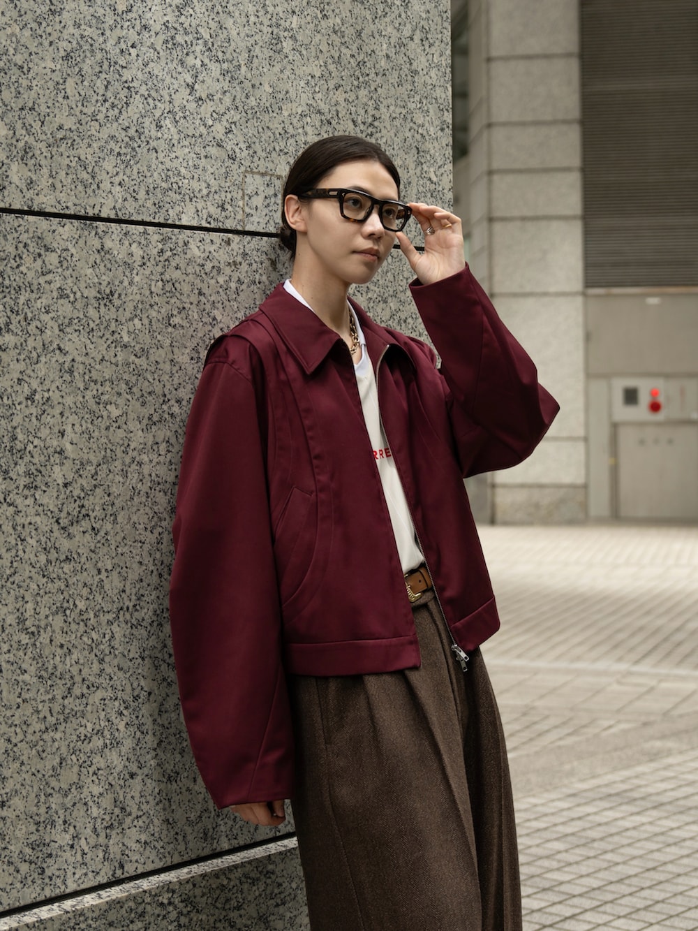 レッド系のブルゾン、ブラウン系のスラックスを着用したメンズの秋コーディネートの3枚目の写真