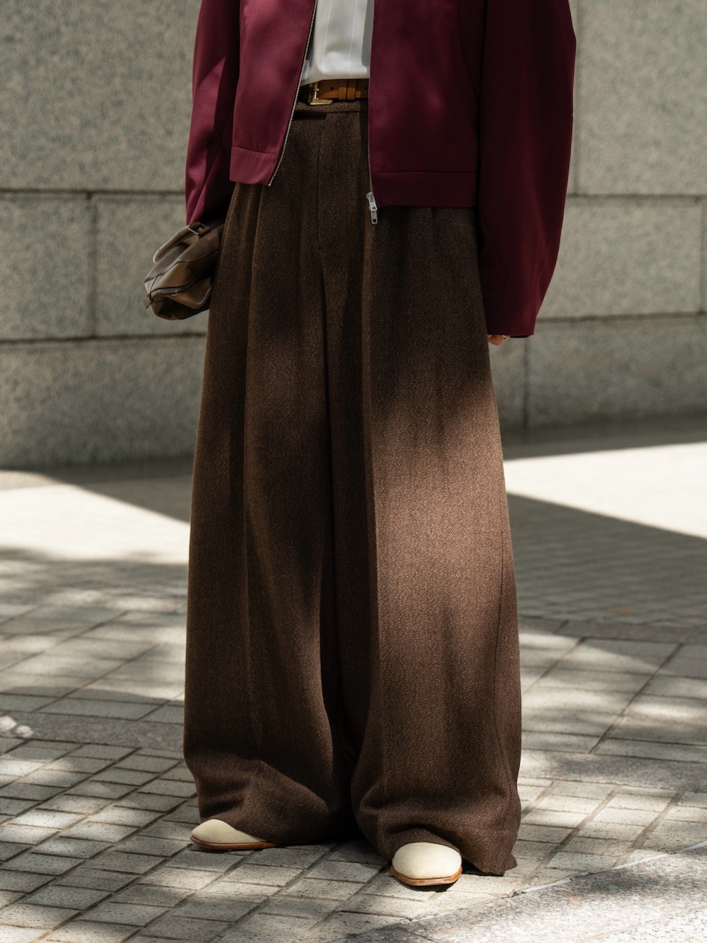 レッド系のブルゾン、ブラウン系のスラックスを着用したメンズの秋コーディネートの2枚目の写真