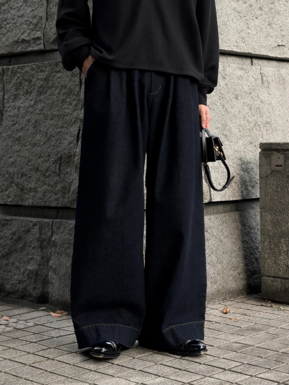 ブルー系のデニムパンツ、ブラック系のハンドバッグ、ブラック系のドレスシューズを着用したメンズの夏コーディネートの3枚目の写真