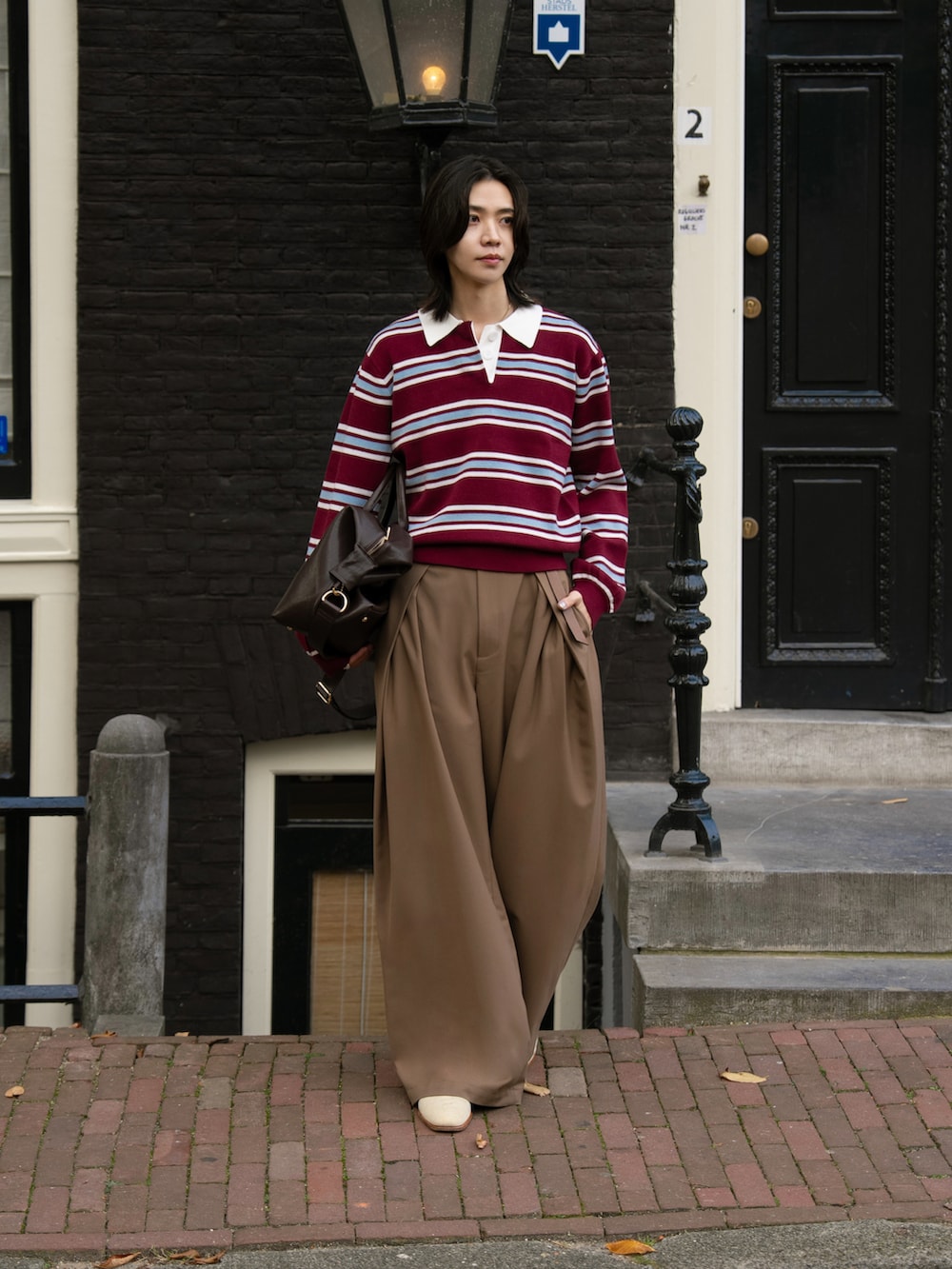 レッド系のポロシャツ、ブラウン系のスラックスを着用したメンズの秋コーディネートの2枚目の写真