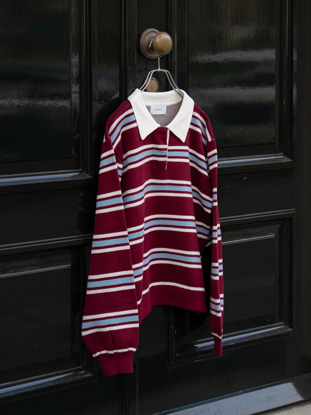 レッド系のポロシャツ、ブラウン系のスラックスを着用したメンズの秋コーディネートの5枚目の写真