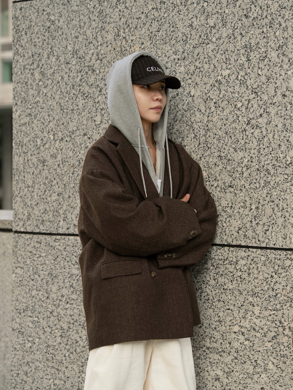 グレー系のパーカー、ブラウン系のテーラードジャケット、ホワイト系のその他パンツを着用したメンズの秋コーディネートの2枚目の写真