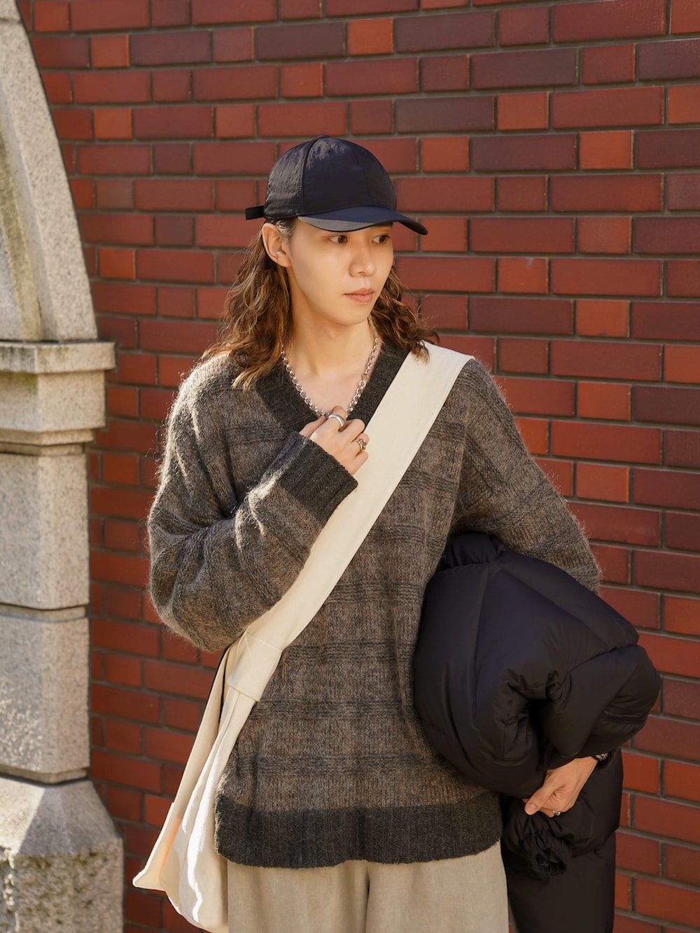 グレー系のデニムパンツ、ブラック系のドレスシューズ、グレー系のニット/セーターを着用したメンズの秋コーディネートの2枚目の写真