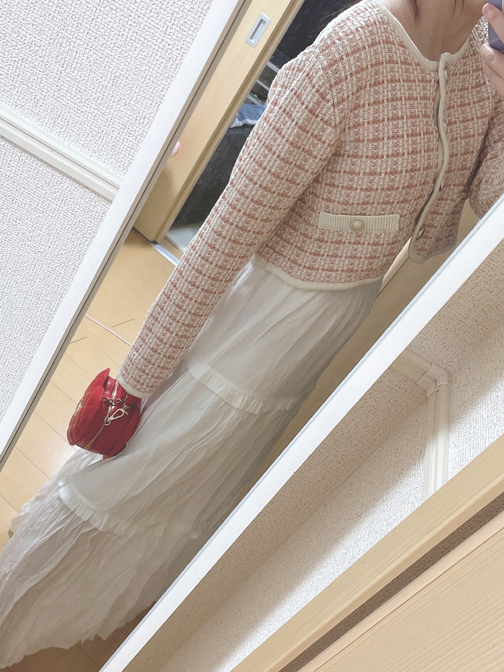 ピンク系のカーディガン/ボレロ、ホワイト系のスカート、レッド系のショルダーバッグを着用したレディースの春コーディネートの2枚目の写真