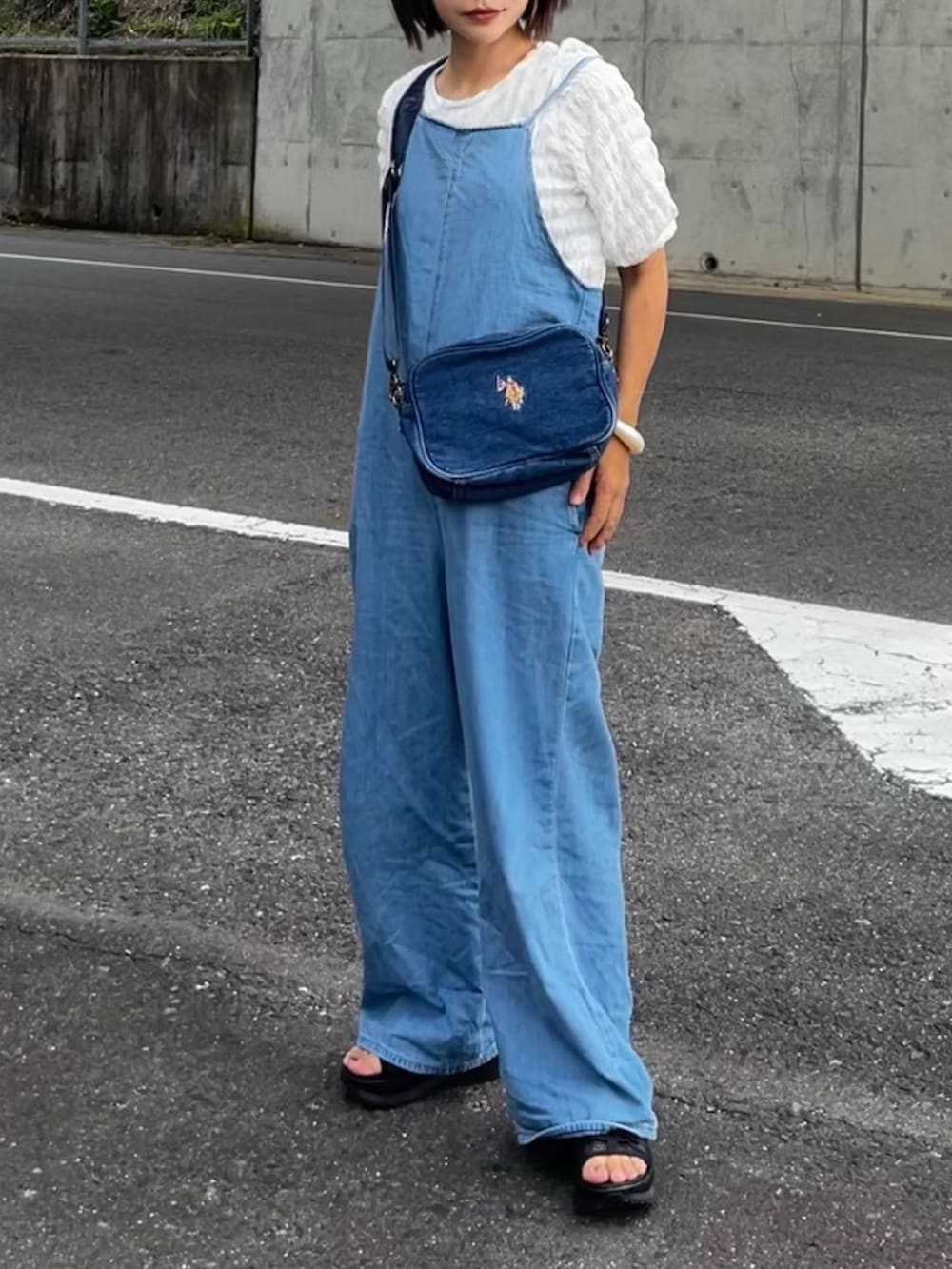 ブルー系のサロペット/オーバーオール、ブルー系のショルダーバッグ、ホワイト系のTシャツ/カットソーを着用したレディースの夏コーディネートの2枚目の写真