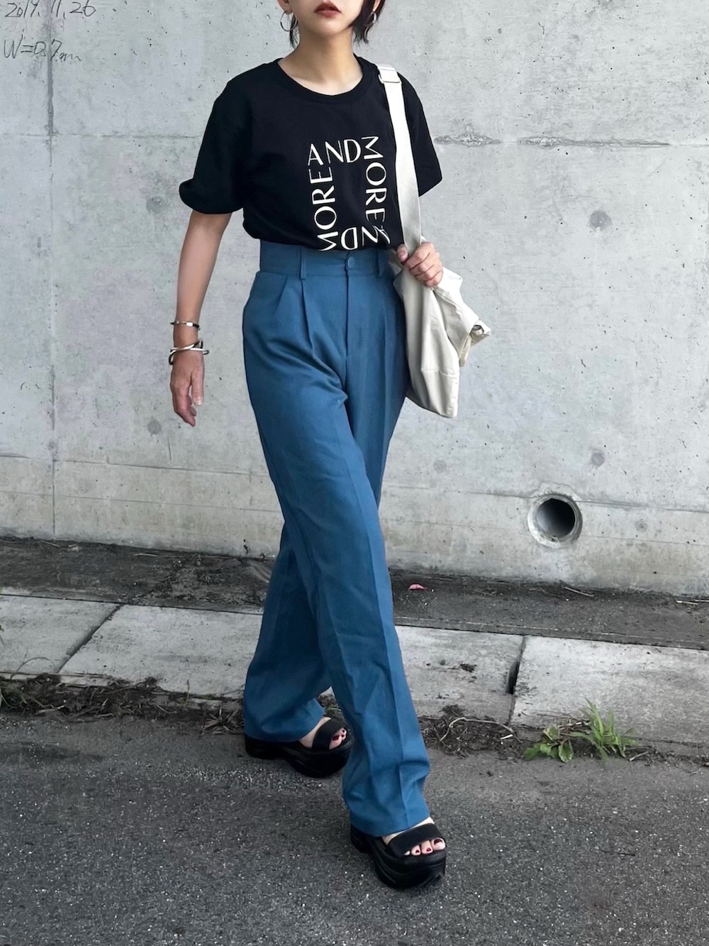 ブラック系のTシャツ/カットソー、ブルー系のスラックス、ブラック系のサンダルを着用したレディースの夏コーディネートの2枚目の写真