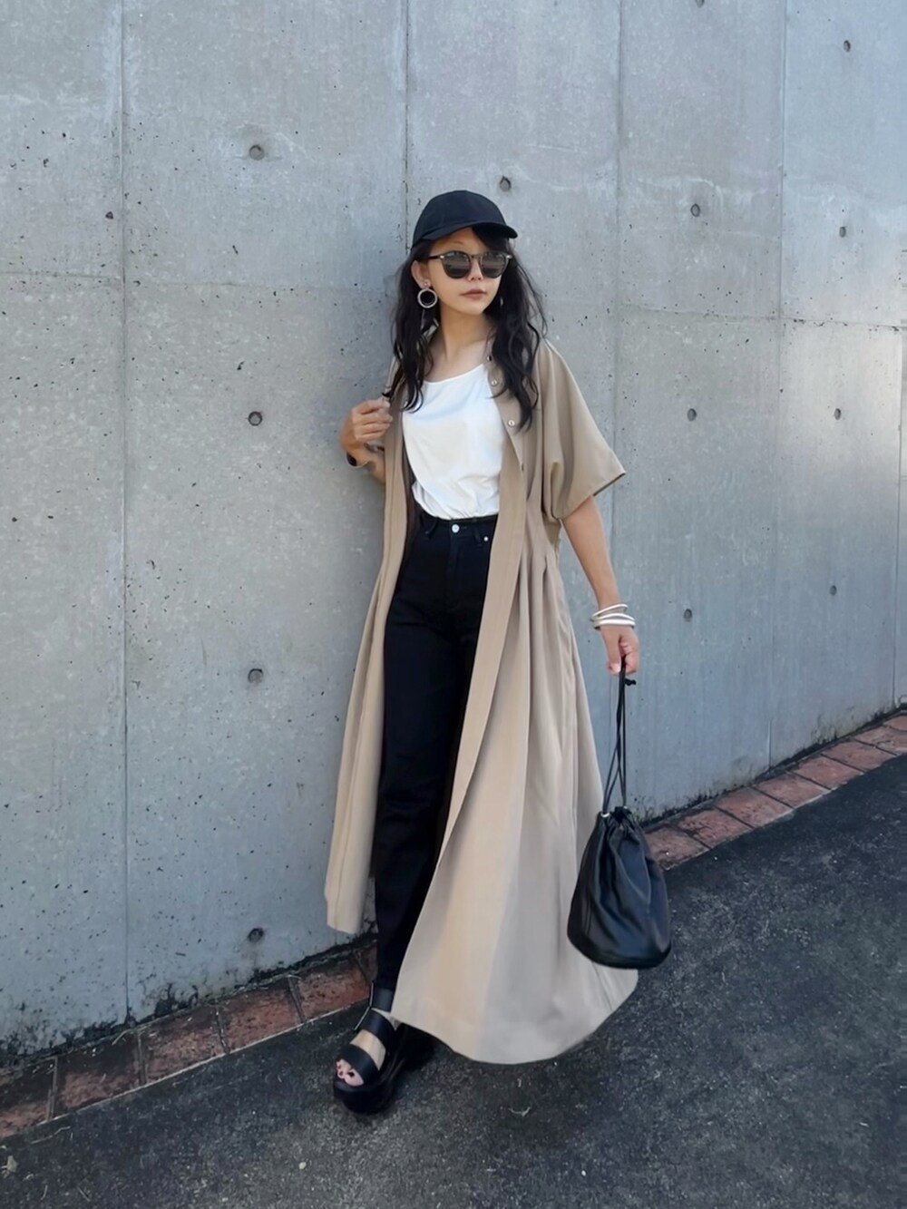 ベージュ系のワンピース、ブラック系のデニムパンツ、ブラック系のサンダルを着用したレディースの夏コーディネートの2枚目の写真