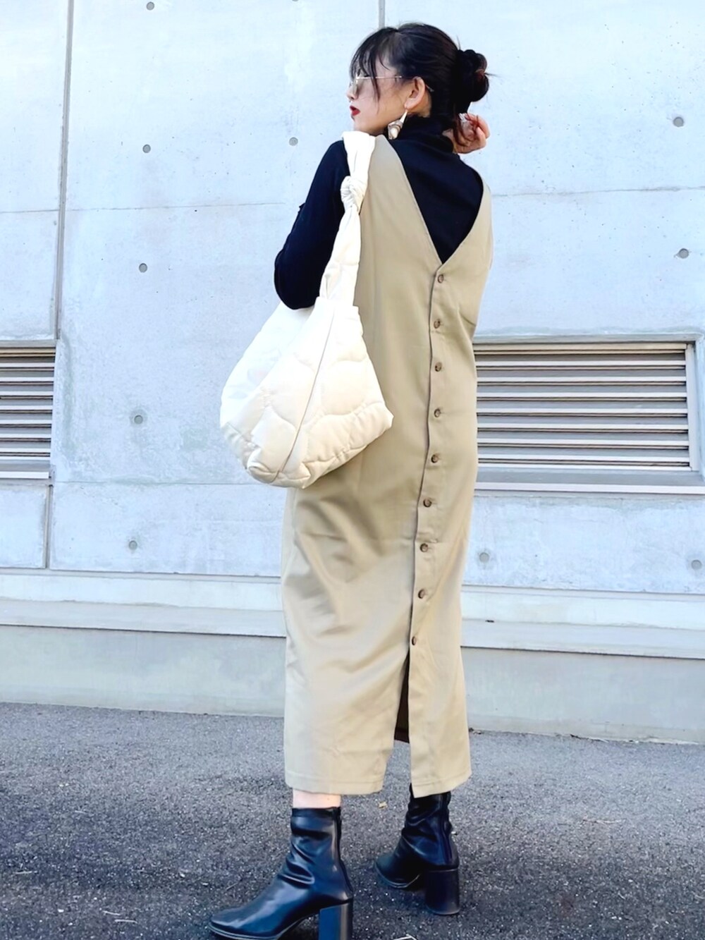 グリーン系のジャンパースカート、ブラック系のTシャツ/カットソー、ホワイト系のショルダーバッグを着用したレディースの冬コーディネートの2枚目の写真